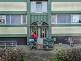 Kvinde med sin postcykel foran en opgang i boligafdelingen Stengårdsvej.